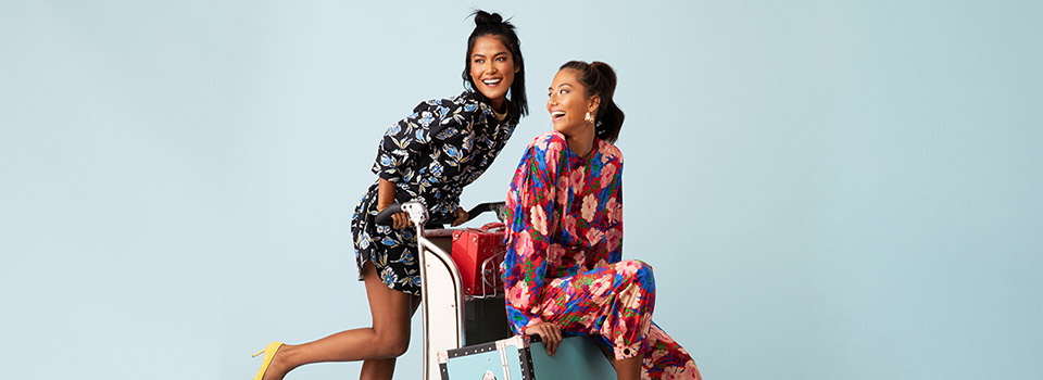 Two women sitting on a luggage cart