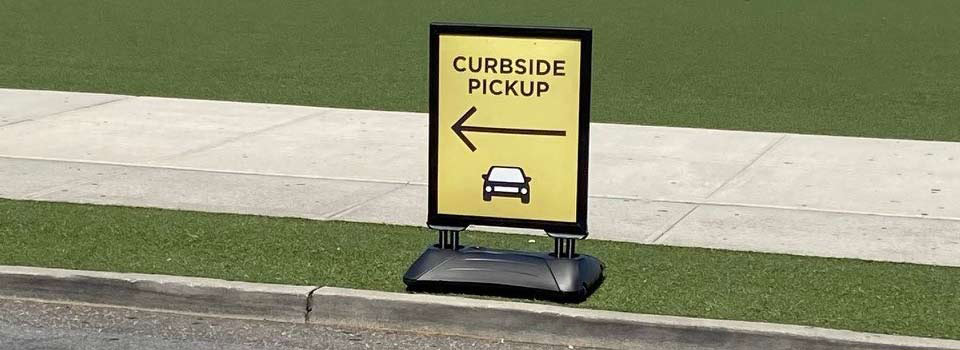 Sign that reads "Curbside Pickup" with an arrow pointing to the left and a car illustration