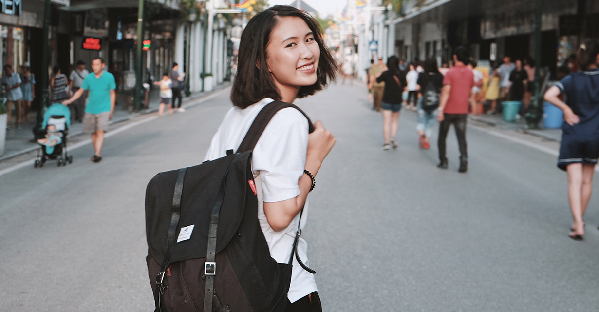 A young woman wearing a backpack on a bustling street