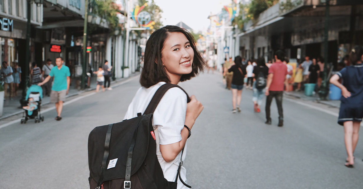 A young woman wearing a backpack on a bustling street