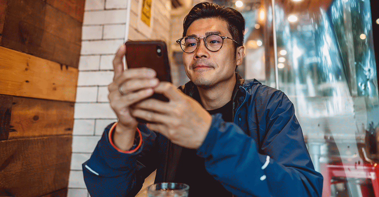 A man in a cafe looking at his phone