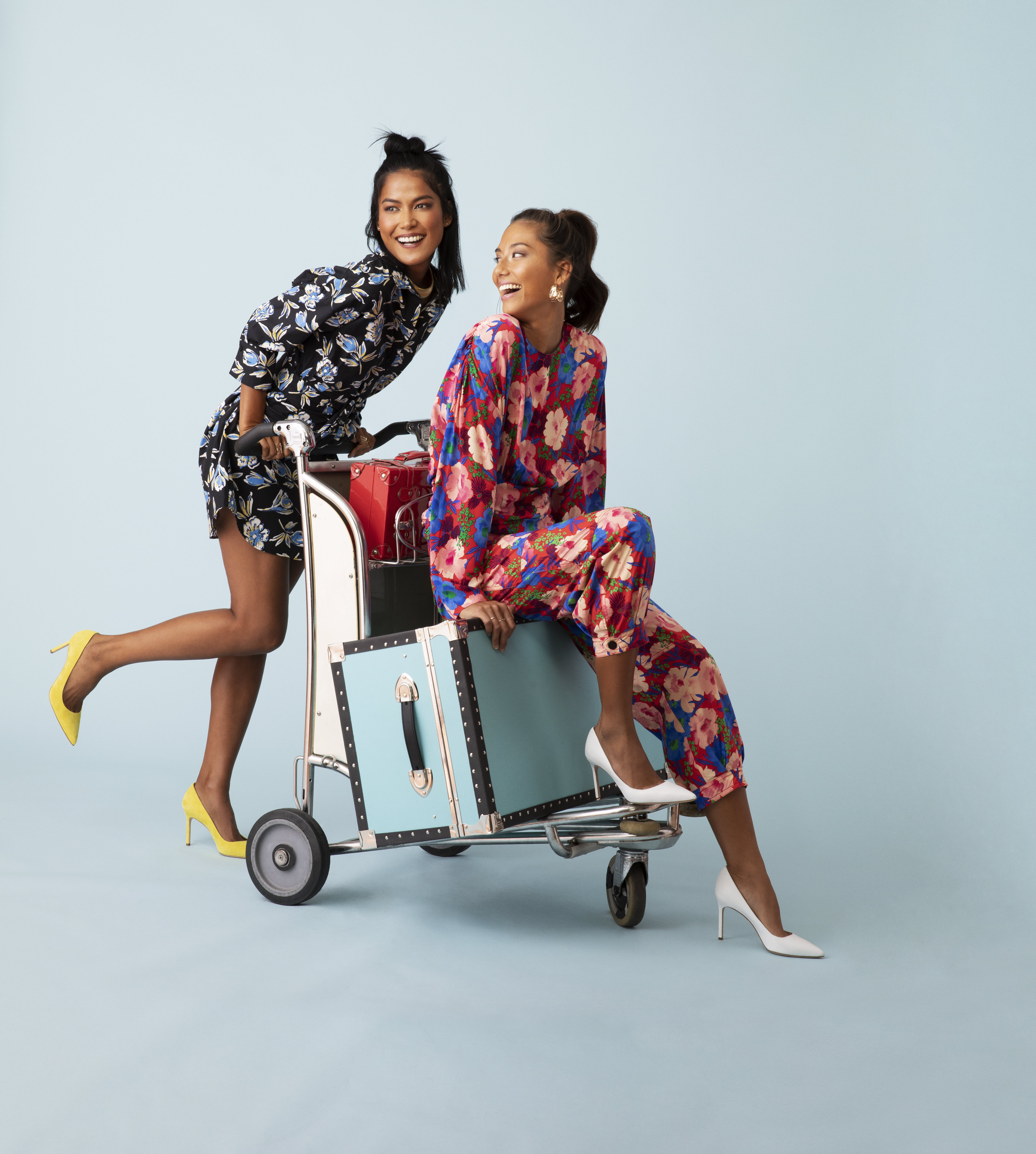 Two women sitting on a luggage cart