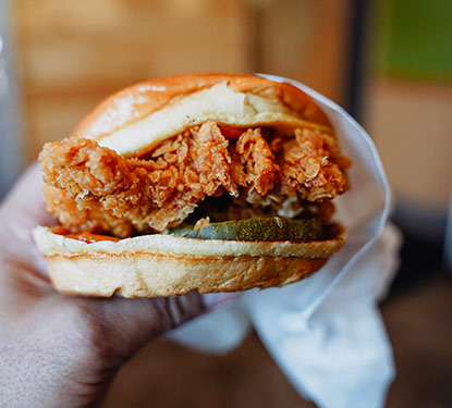 A hand holding a fried chicken sandwich