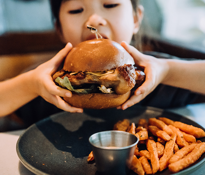 A girl biting into a chicken sandwich