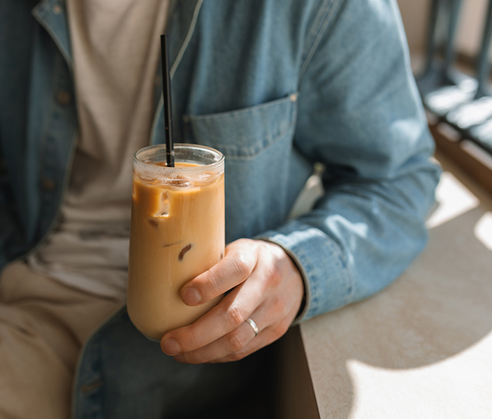 A man drinking an iced coffee at a cafe