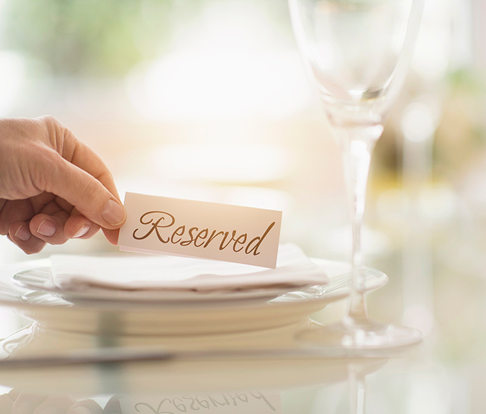 A hand placing a Reserved sign on a restaurant table
