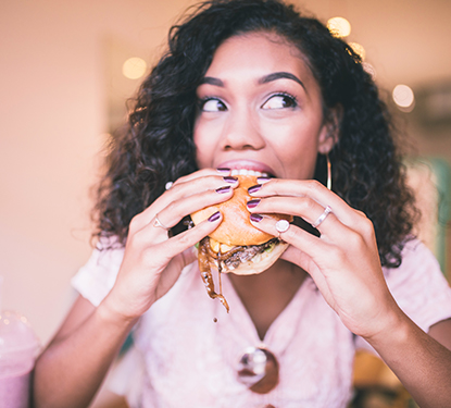 A woman eating a juicy cheeseburger