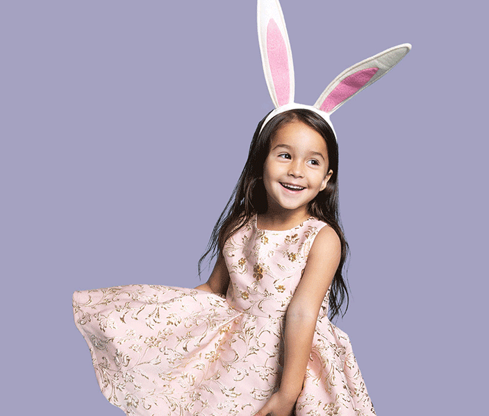 A girl twirling in an Easter dress and wearing an Easter Bunny ears headband