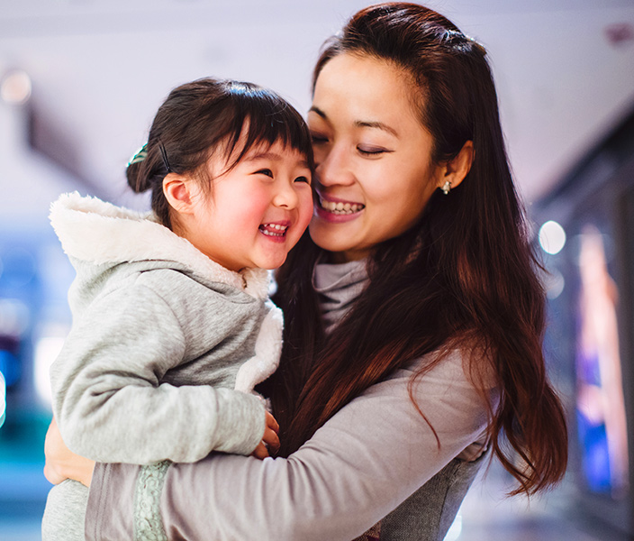 A mother holding her toddler daughter