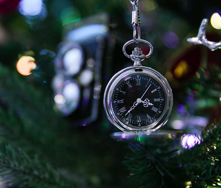 A silver pocket watch on a holiday tree