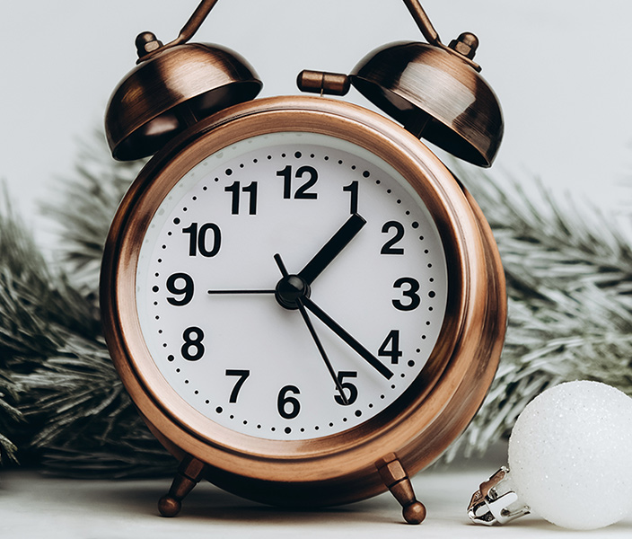 An alarm clock, snowy pine branches and holiday ornaments