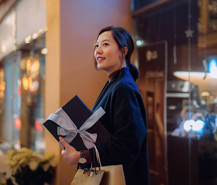 A glamorous woman holding a wrapped present while shopping