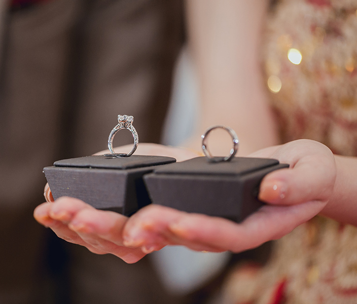 A woman holding a diamond and a silver ring in display boxes in her hands
