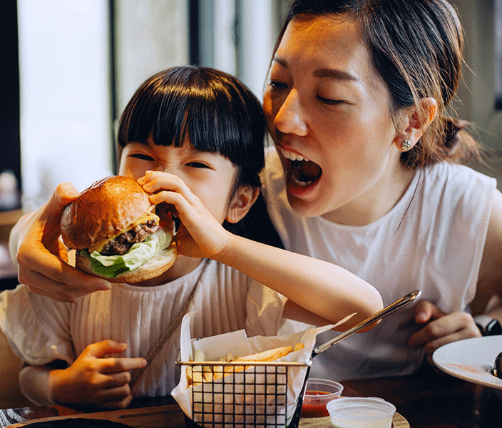 A mother and daughter eating a restaurant burger