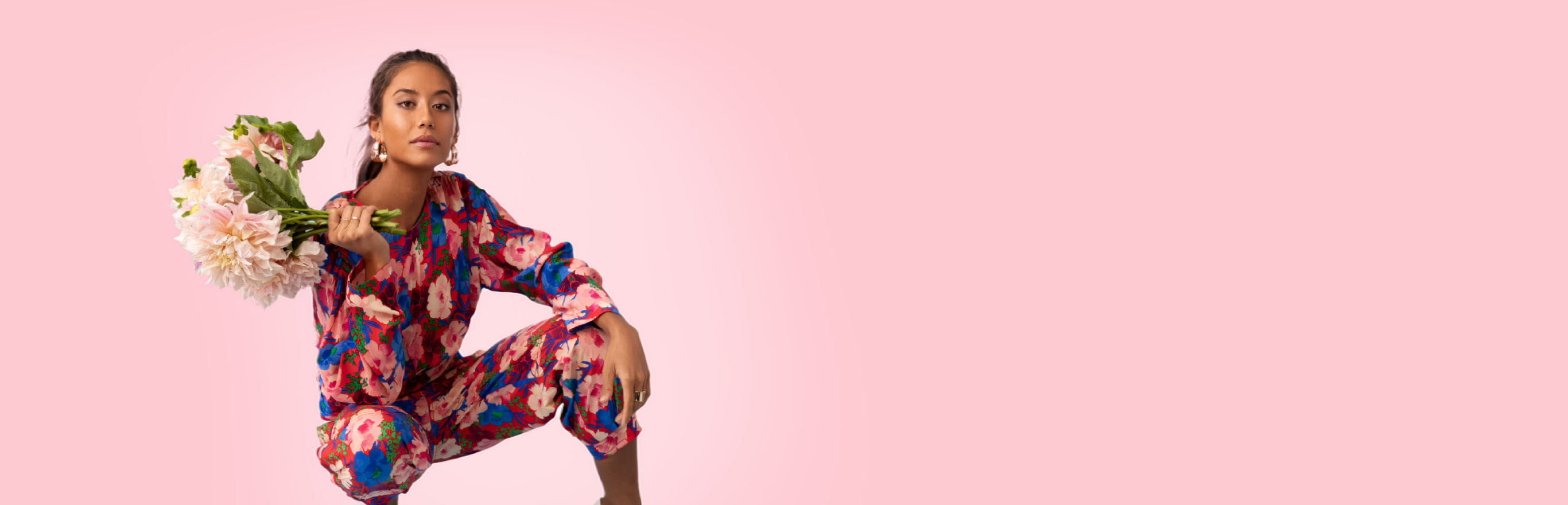 A woman in a floral jumpsuit holding a bouquet