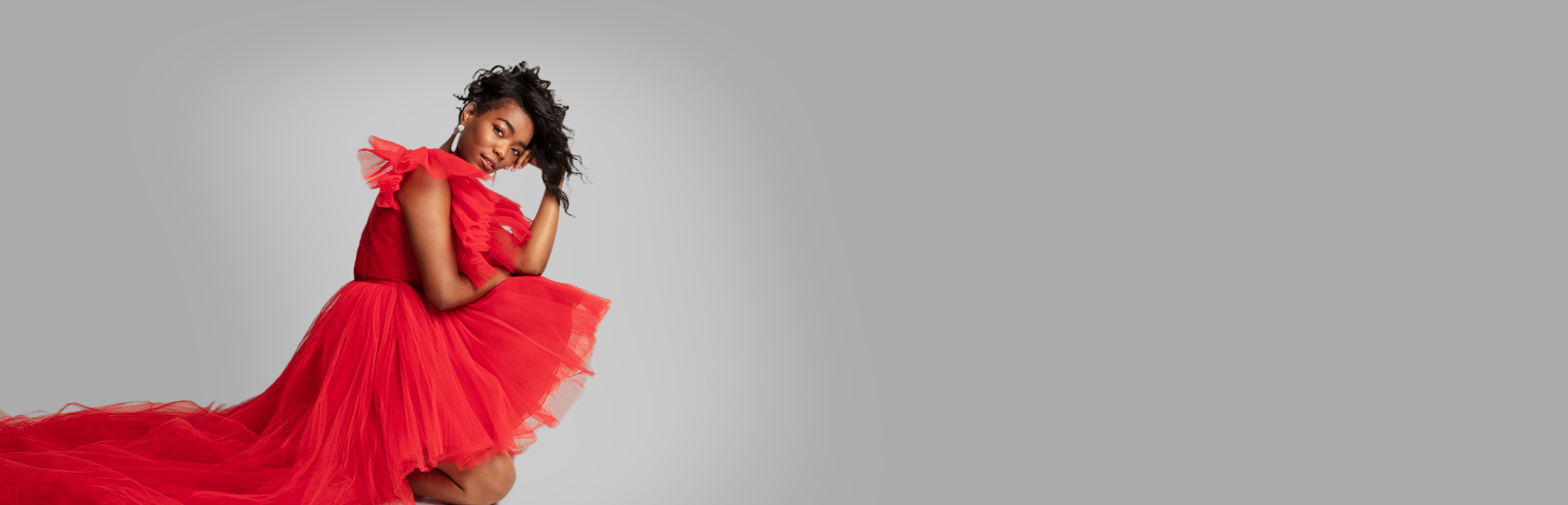 A woman kneeling in a flowing red holiday dress