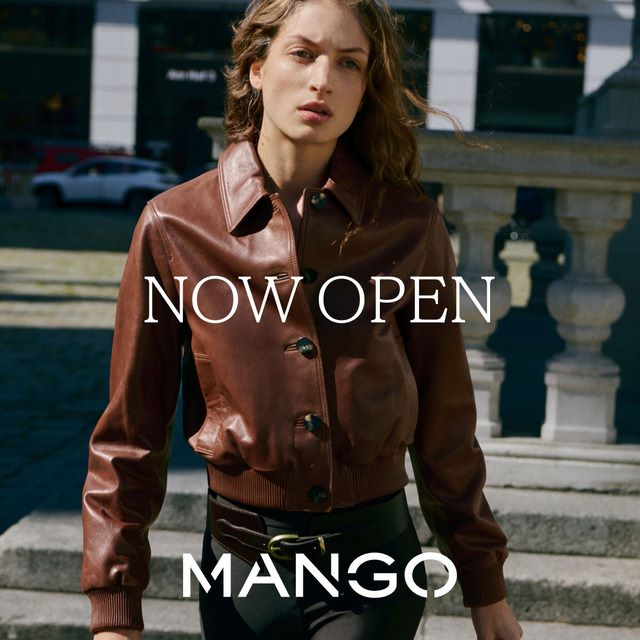 A woman wearing a burgundy leather shirt walking down the street, image says Now Open Mango