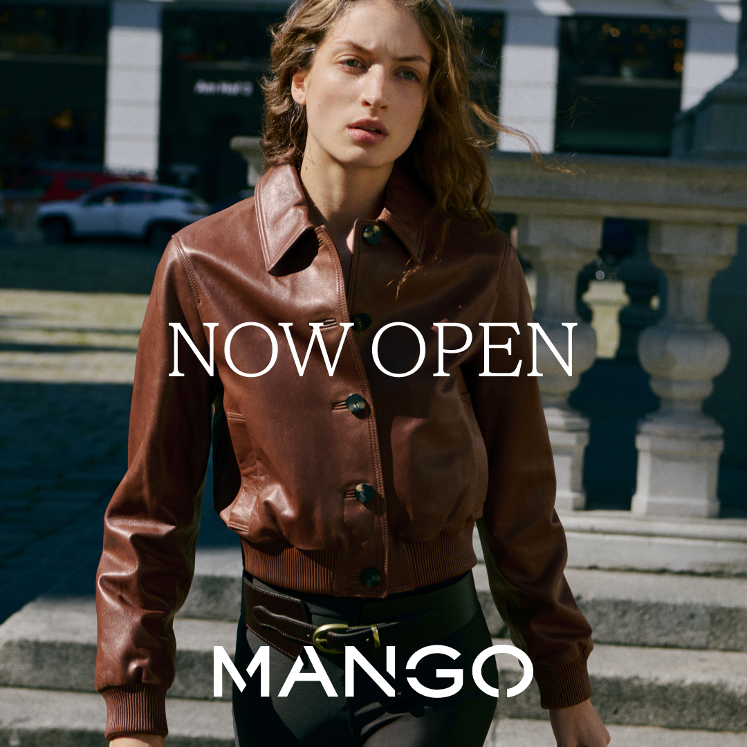 A woman wearing a burgundy leather shirt walking down the street, image says Now Open Mango