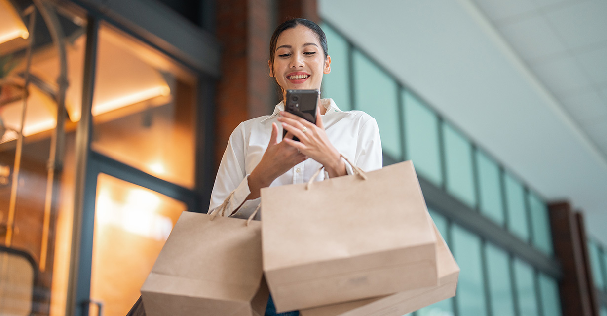 A woman holding shopping bags and looking at her phone
