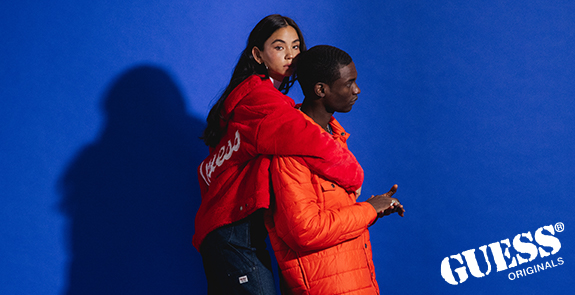 Man and women wearing orange and red jackets on a blue background.  Guess Originals Logo