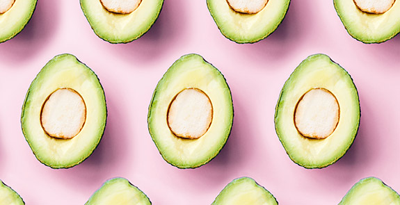 Avocado halves arranged on a pink background