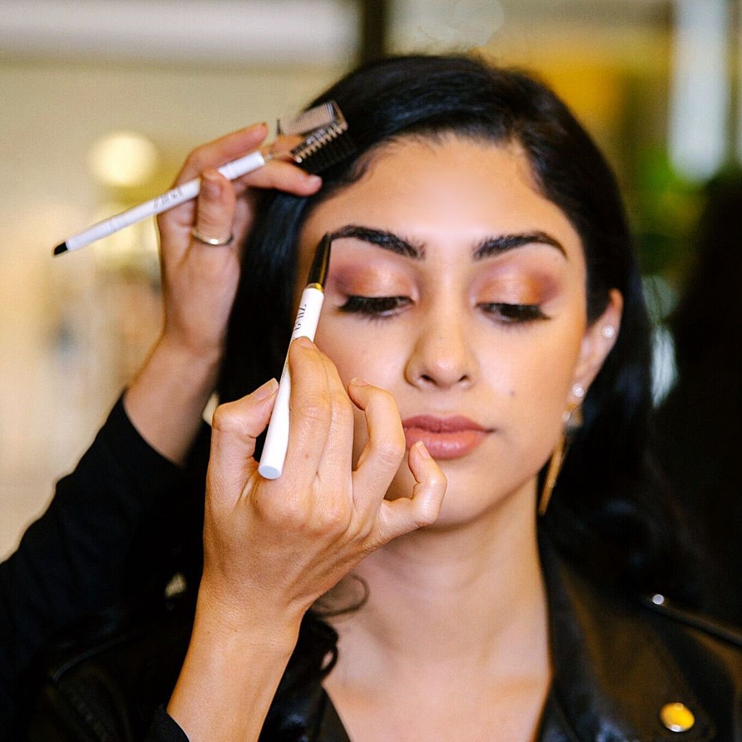 Close up of women's face with eyebrow pencil being applied