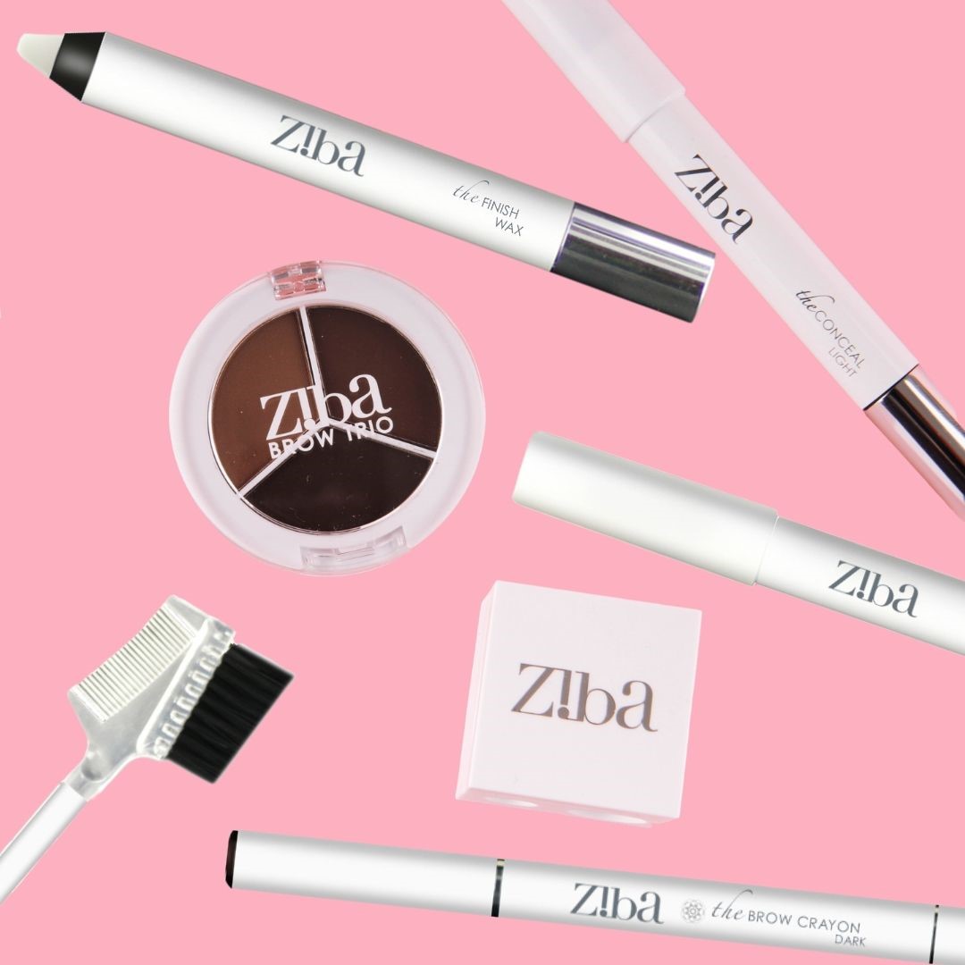 Ziba cosmetic crayons, pencils brushes and cosmetics laid out on a pink background