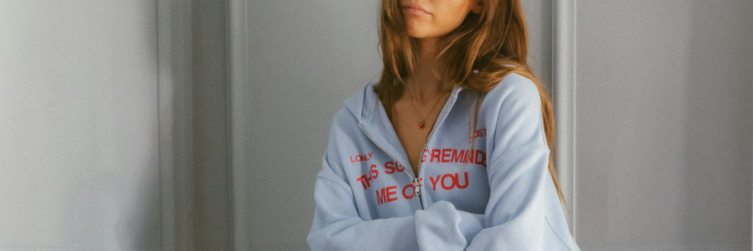 woman in hoodie in front of off-white wall