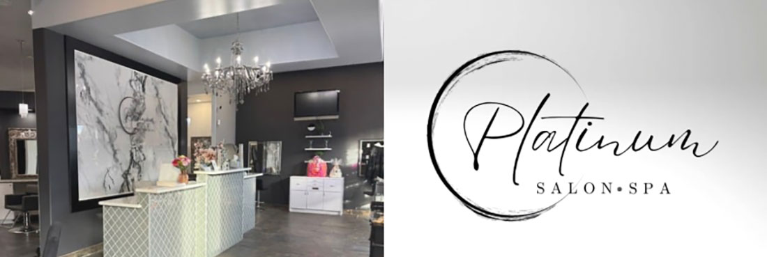 Platinum Salon & Spa interior featuring a modern reception desk, chandelier lighting, and dark-toned styling stations, alongside the salon’s circular logo with elegant script lettering.