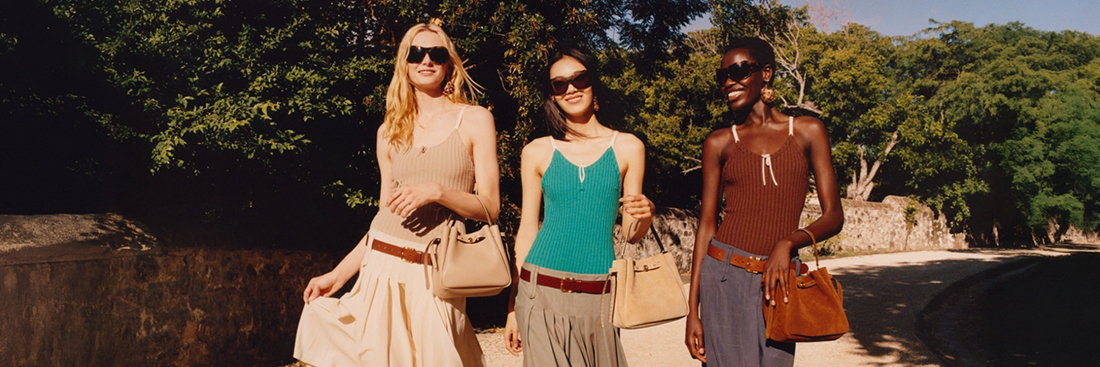 Three woman walking outside on a trail and looking very fashionable in tanktops and bags